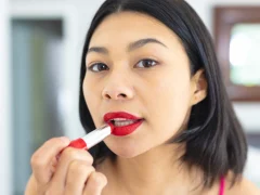 Une femme avec une petite bouche qui applique un rouge à lèvre rouge
