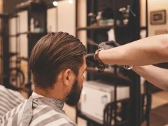 Un homme avec les cheveux mi-longs qui entretien ses cheveux chez le coiffeur