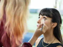 Une femme qui se fait mettre du khôl en poudre sous les yeux par une maquilleuse professionnelle