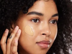 une femme à la peau claire qui applique un fond de teint